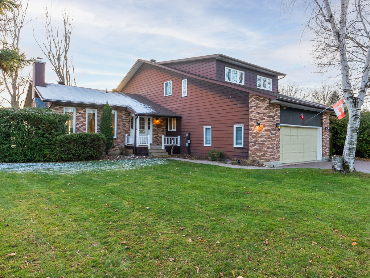 The front of a two-story home with a built-in two-car garage, a long driveway, and a big grassy yard.