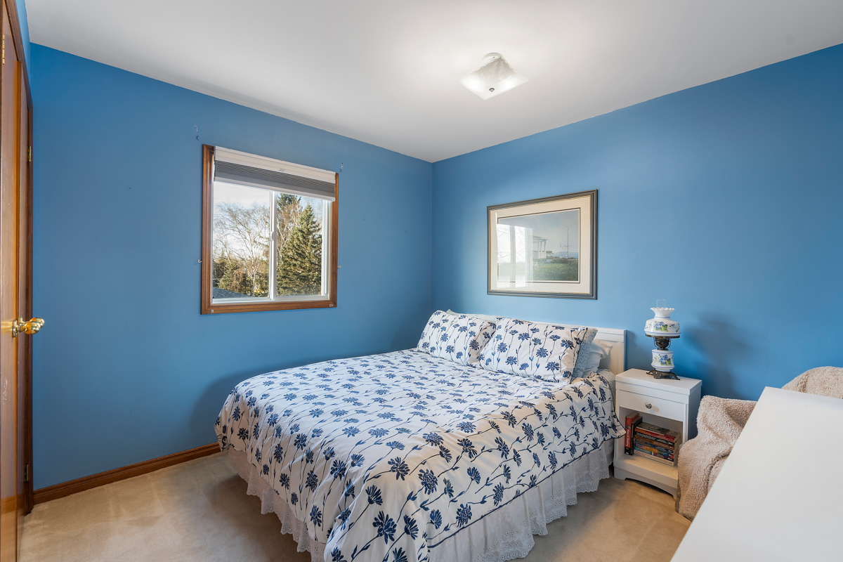 A small bedroom with sky blue walls and a big bed.