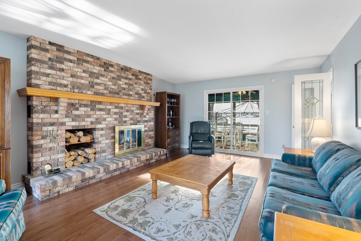 A bright living area with a couch and a big coffee table. One wall has stone from floor-to-ceiling, with a fireplace in the centre.