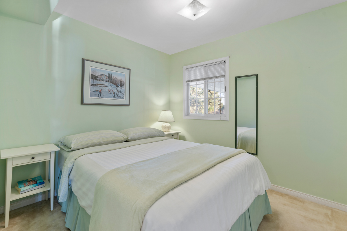 A small bedroom with a big bed and light green walls.