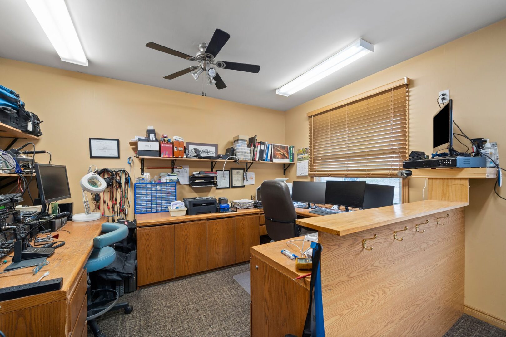 A wide home office space with deck wrapping around three walls and two desk chairs.