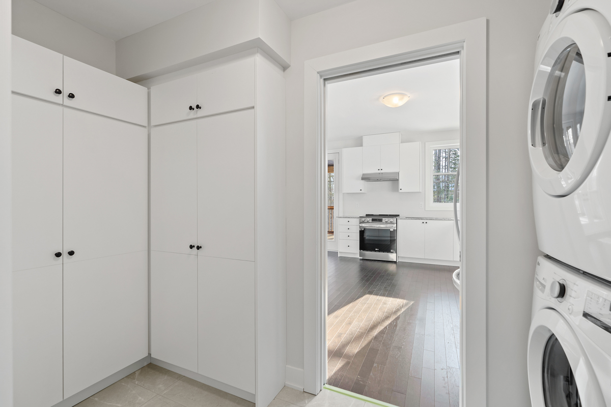 A small space with floor-to-ceiling white cupboards. A doorway leads out to a bright kitchen space.