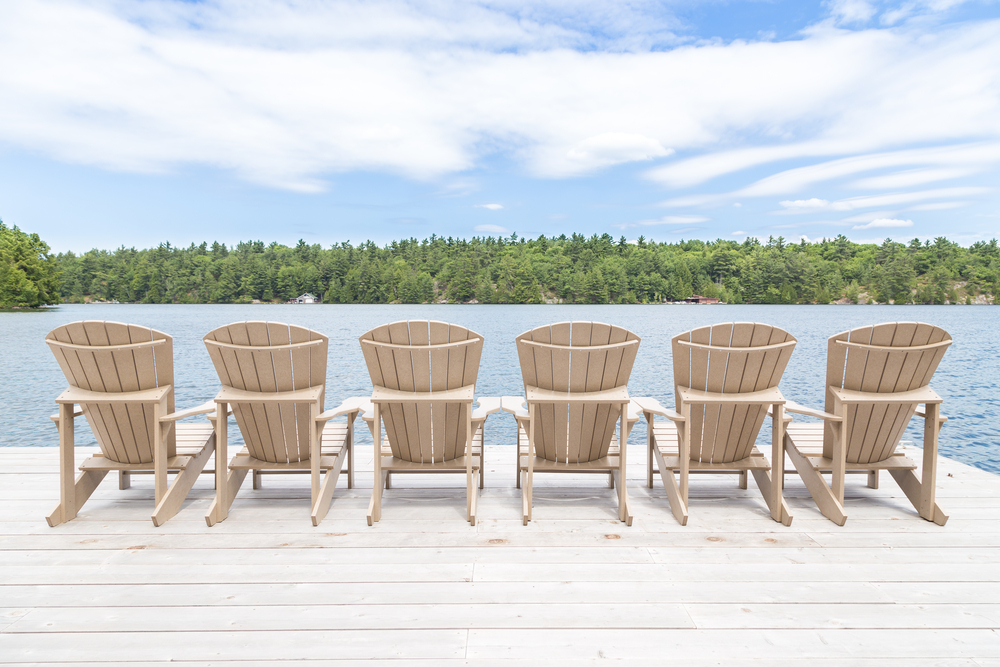 Row of Muskoka chairs on a dock looking onto the lake. short-term rental