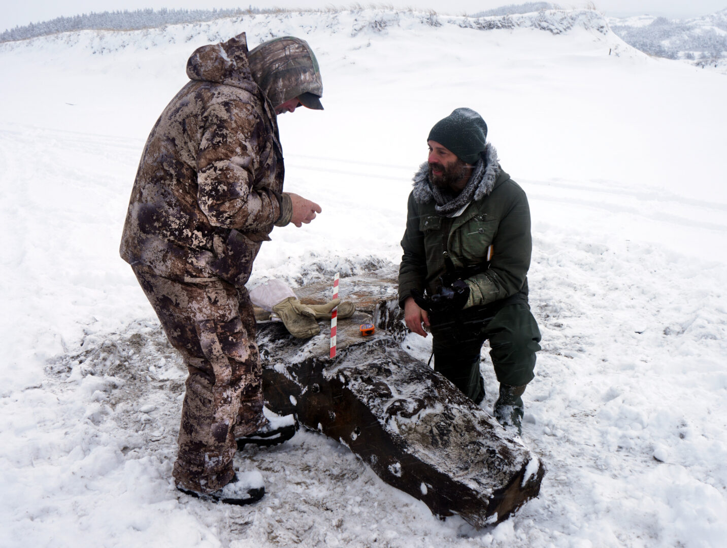 Two men inspecting part of the wreck.