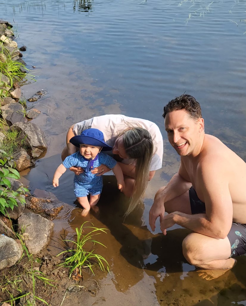 natalie and her husband and son wade in the water together