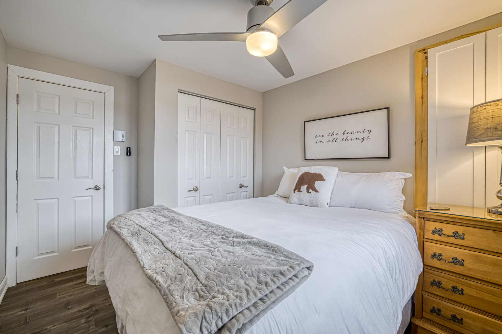A cozy bedroom with a big bed, a wooden dresser, and beige-painted walls.