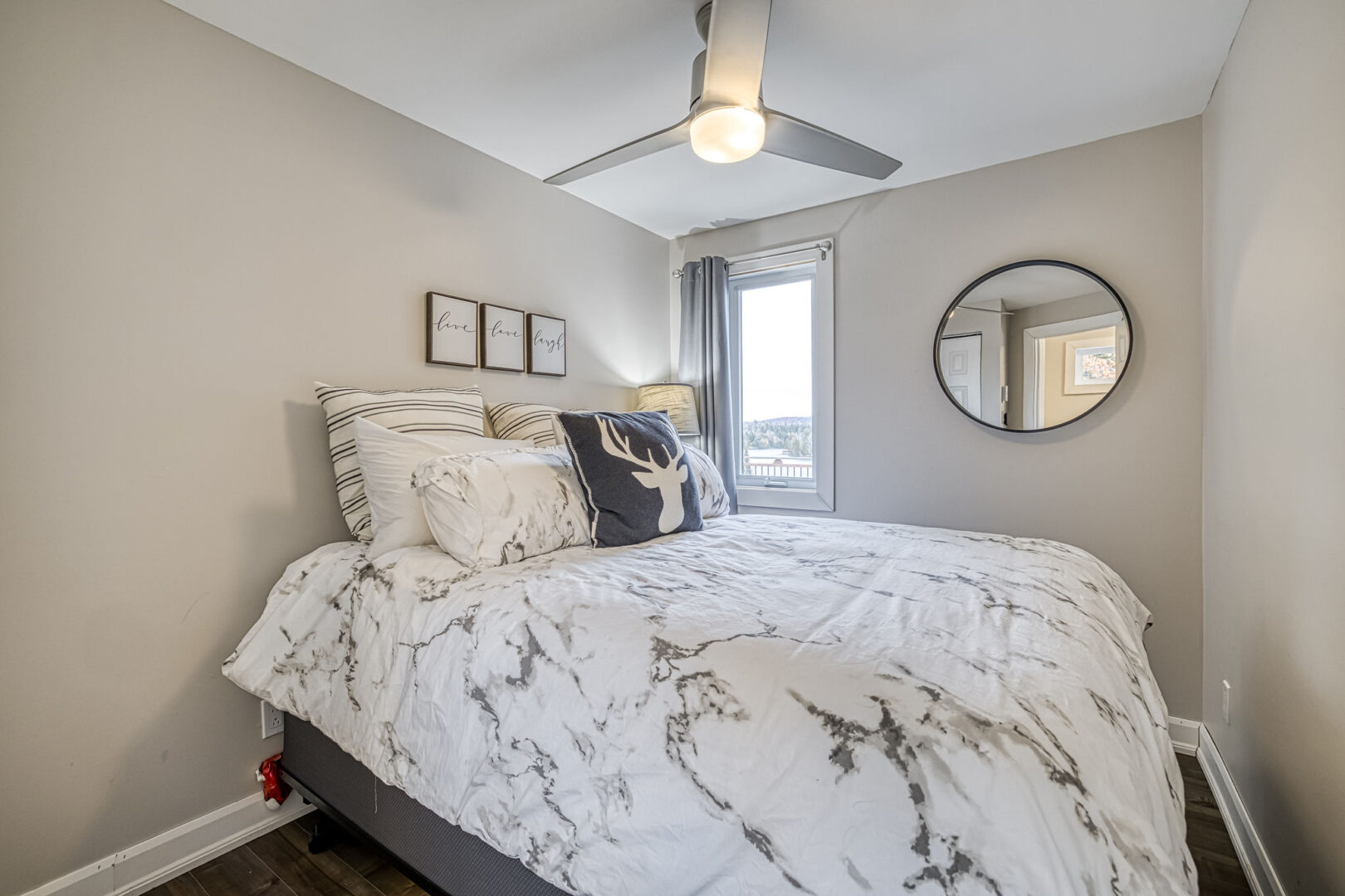 A small bedroom with a big bed, a small window, and beige-painted walls.