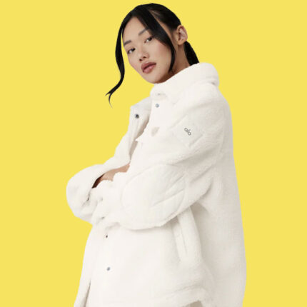 a woman wearing a white sherpa shacket against a yellow background