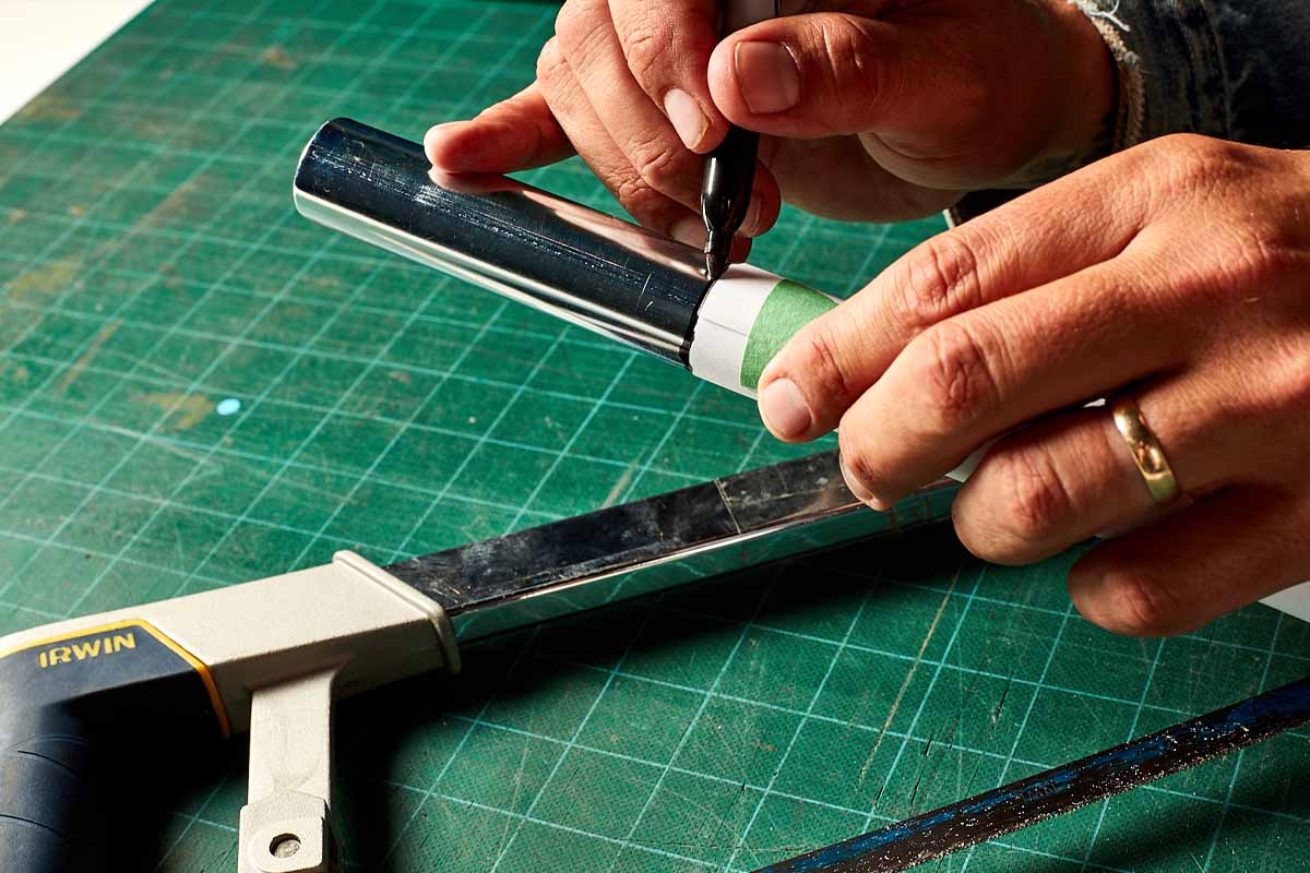 Hands using a wrap of paper to make a square cut in a piece of pipe