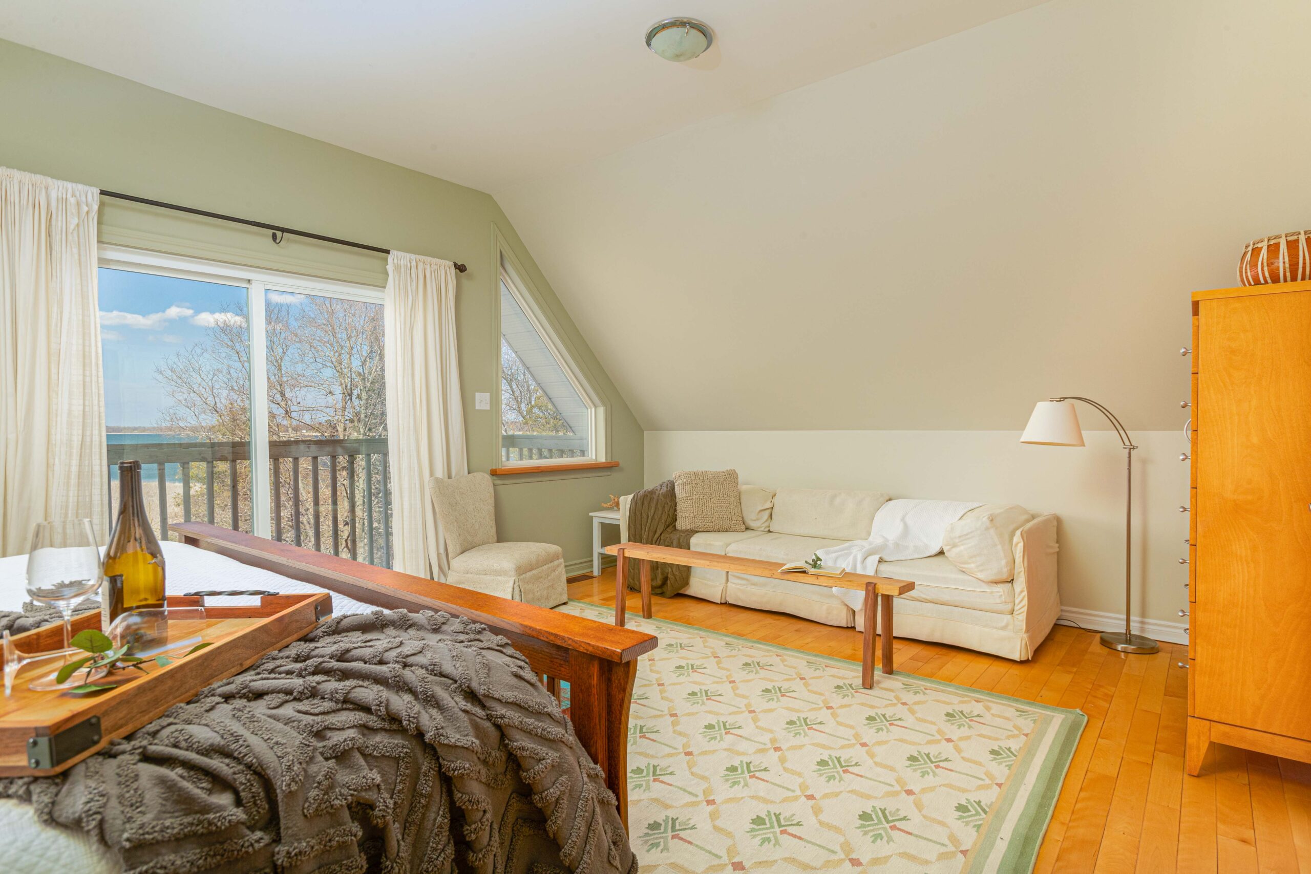 A big bedroom with a bed and a couch. Sliding glass doors open out to an exterior balcony.