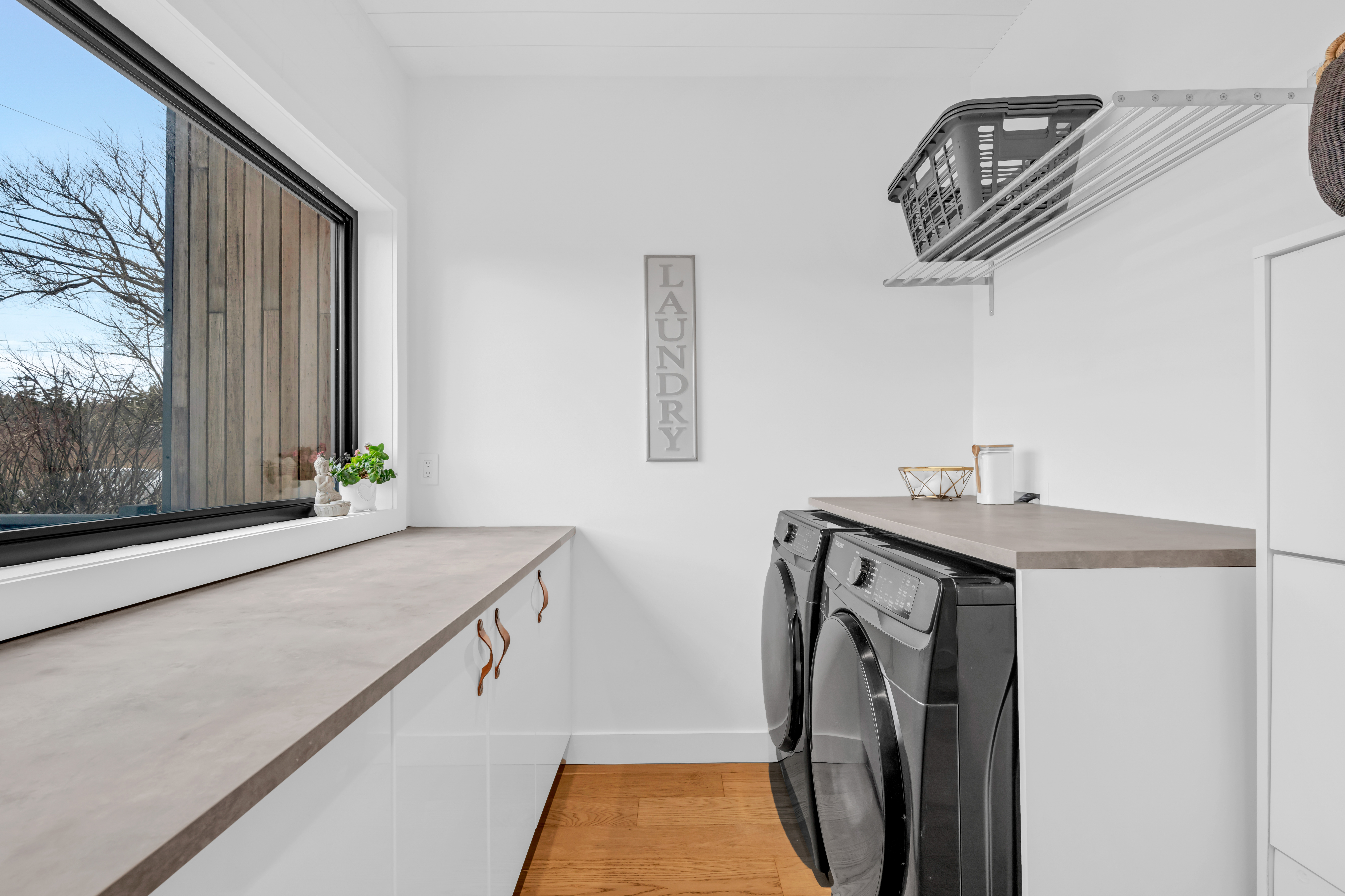 A bright laundry area with a big window, a washer and dryer, and lots of cupboard and counter space.