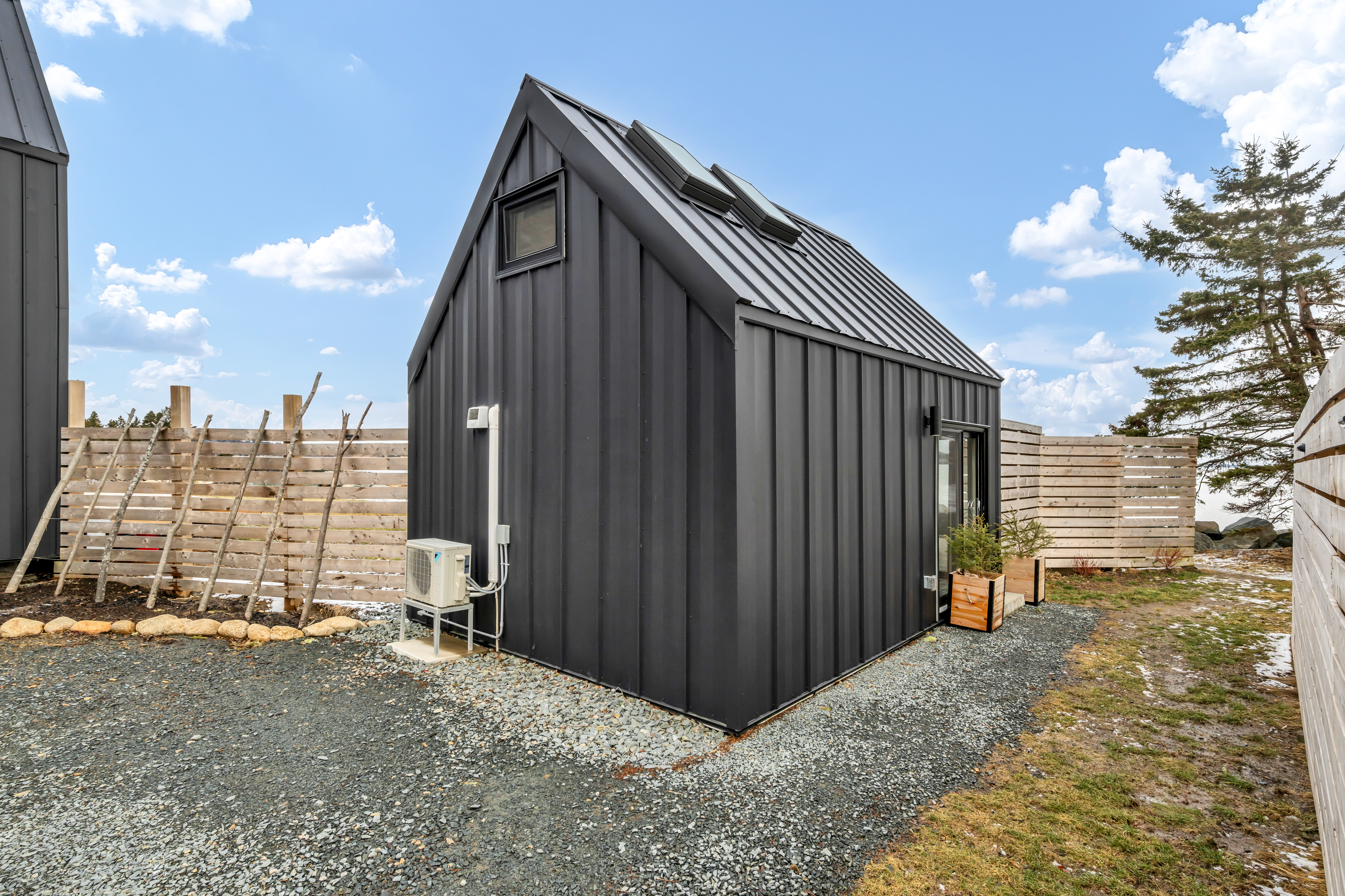 The back of a small oceanfront guest home with black siding.