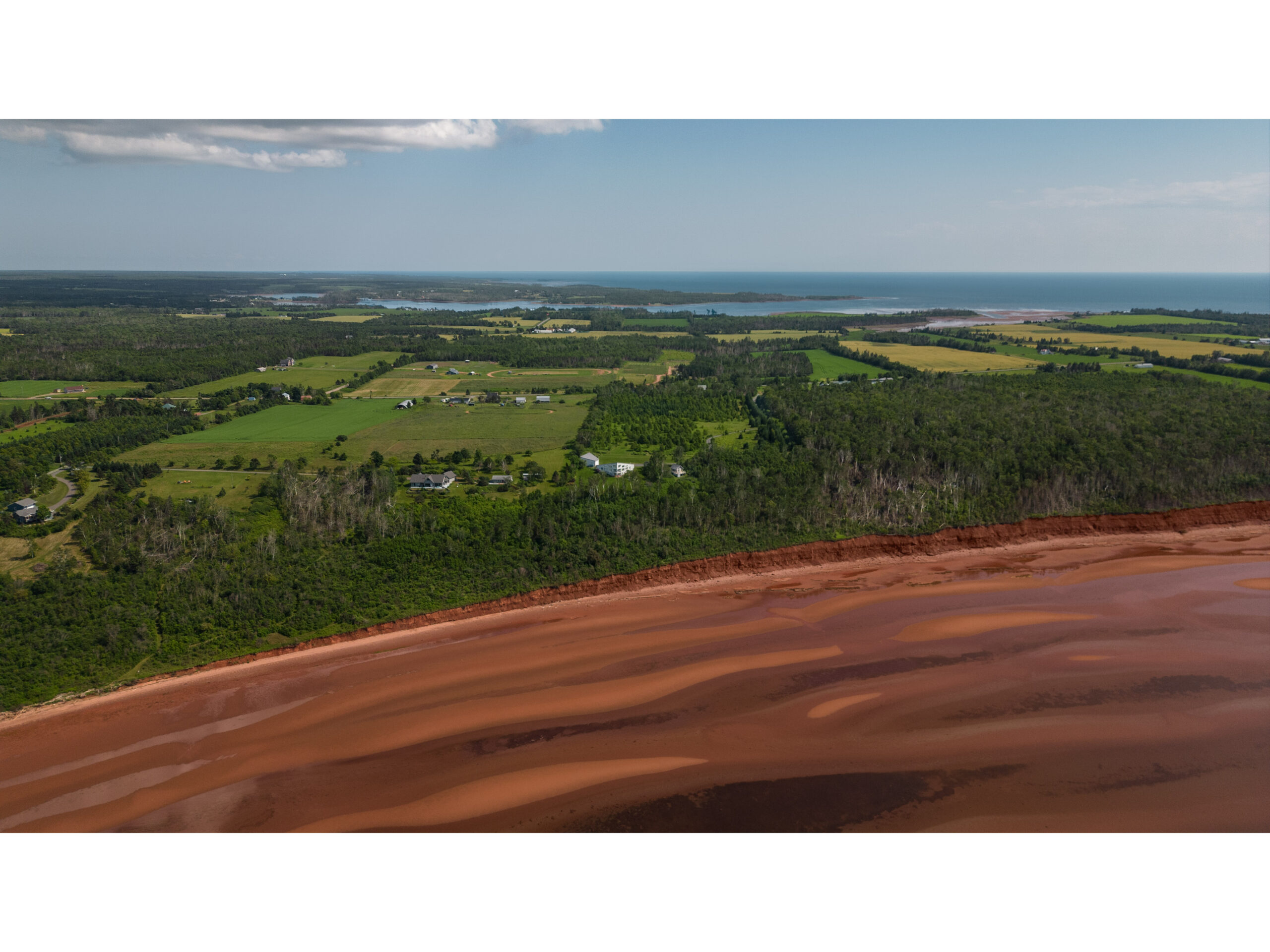 A red sand beach with green trees extending behind.