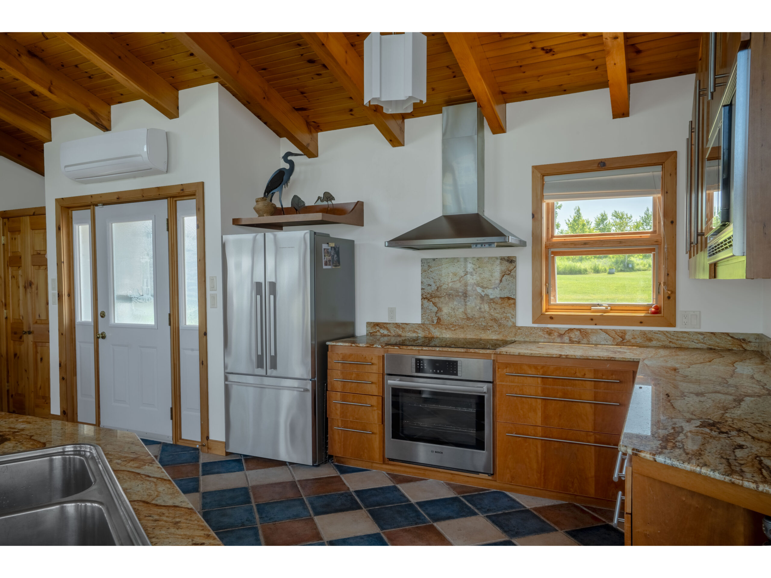 A big kitchen with a colourful tiled floor, stainless steel appliances and granite countertops.