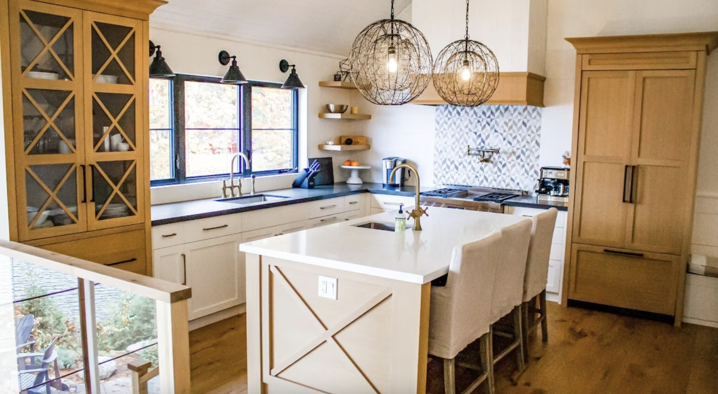 white kitchen with two circular metal lighting fixtures and island and a sink