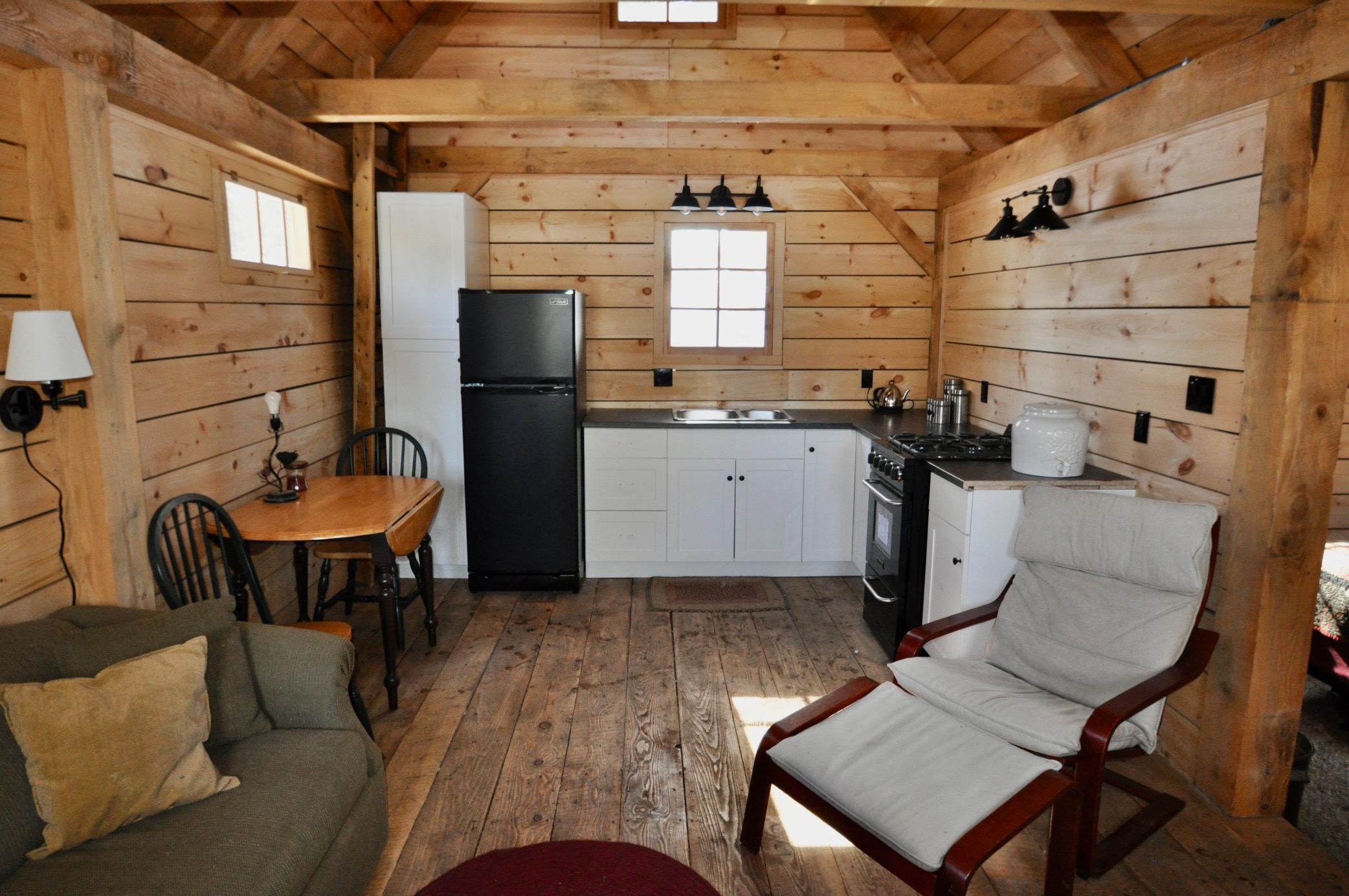A cozy interior of a wood cabin, with an open-concept living and kitchen area.