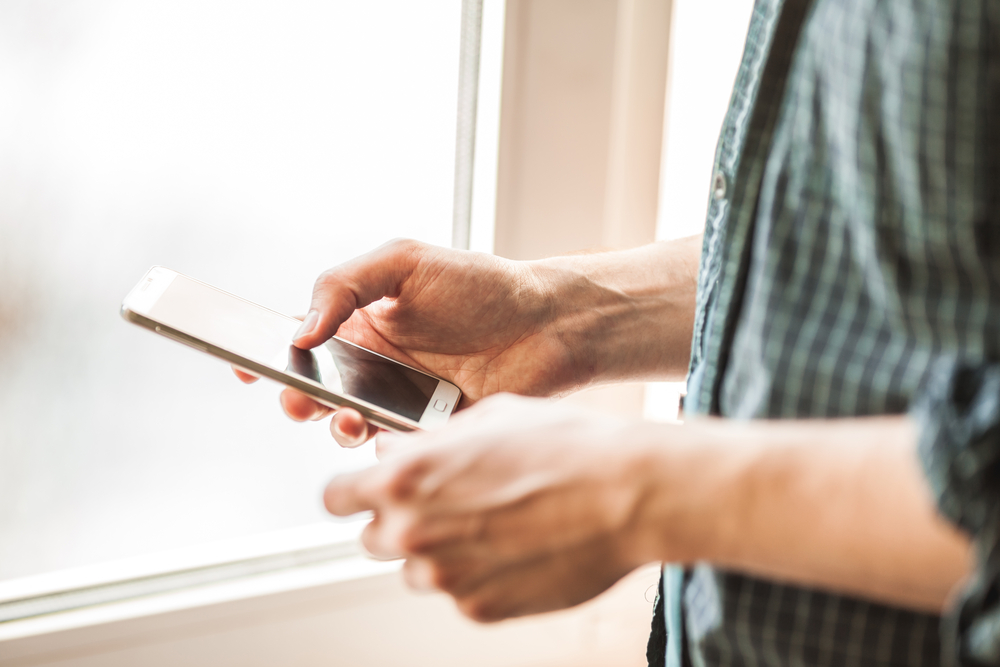 Man holding mobile phone in his hands, using mobile phone close-up shot. Man dialling a hotline number on his phone