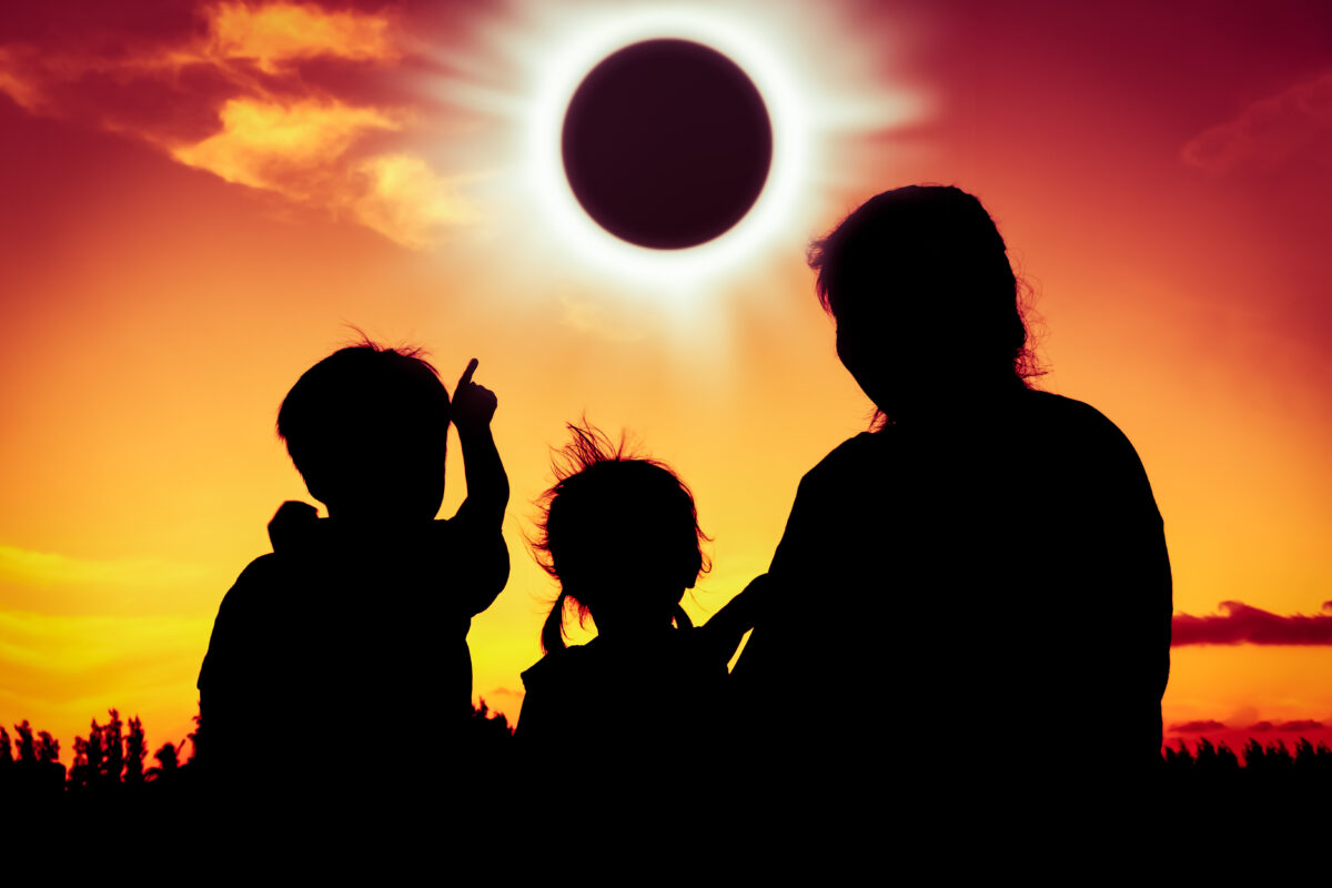 three people watching a solar eclipse