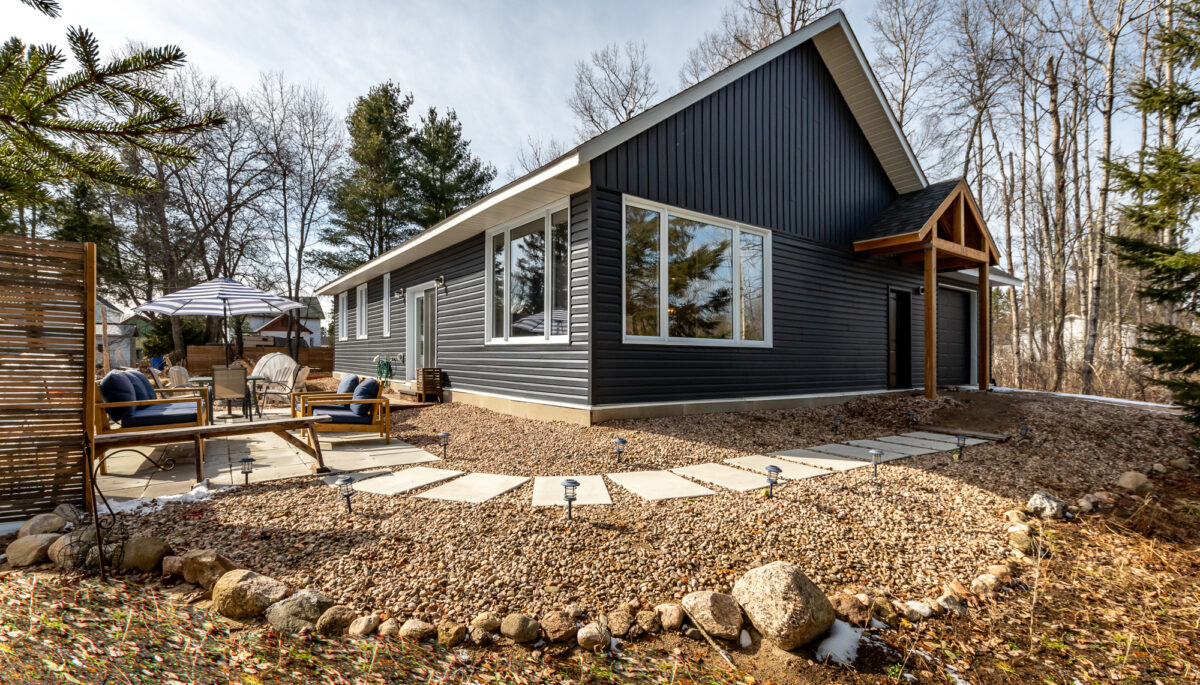A blue-panelled house that sits on a large property with stepping stones that wrap around the hosue