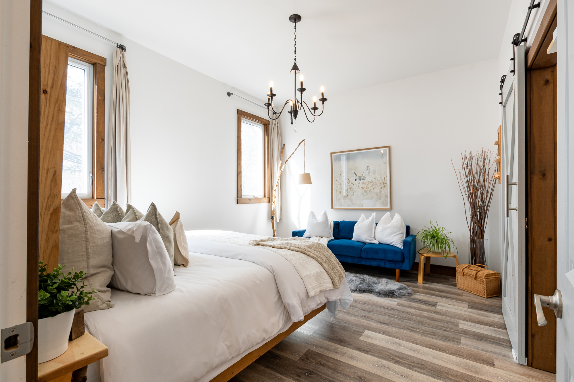 The white bed faces a blue couch