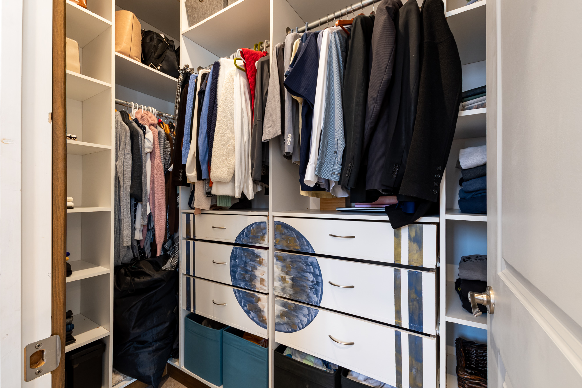 An open closet with drawers near the ground and hangers on top