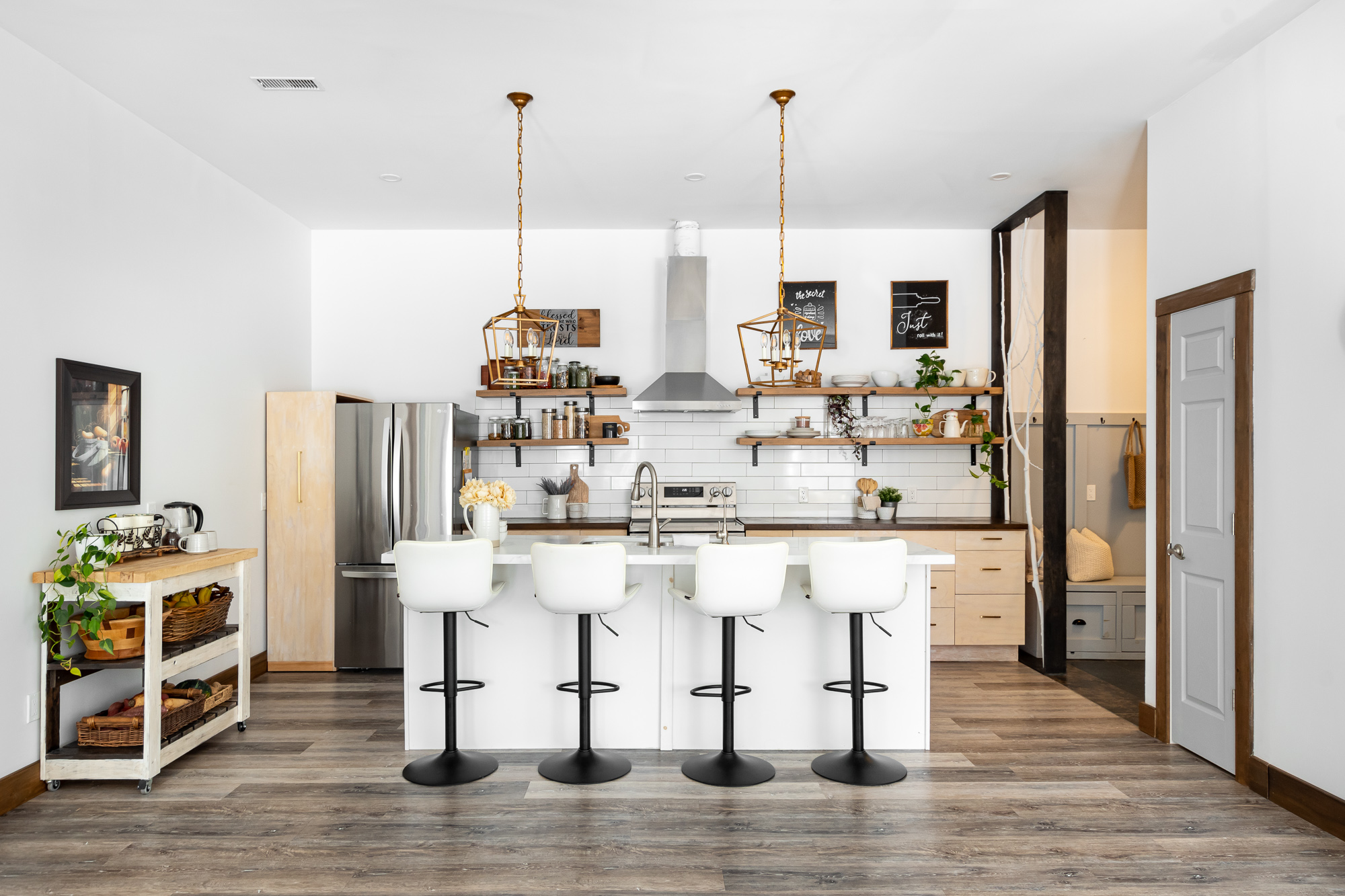 A bright kitchen with a white kitchen island, bar stools, and cooking area behind.