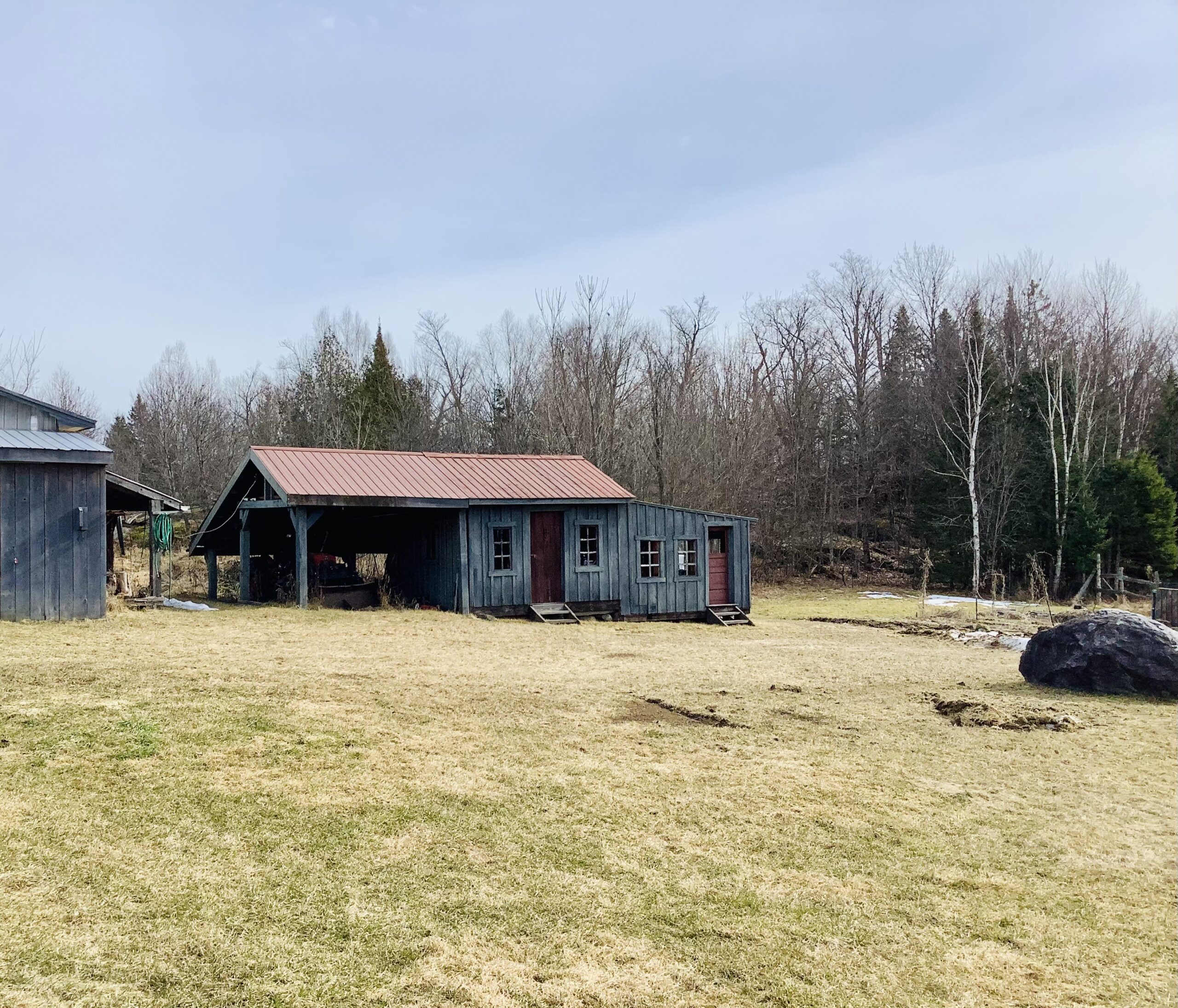 A small, rustic wooden building in the middle of a big field.