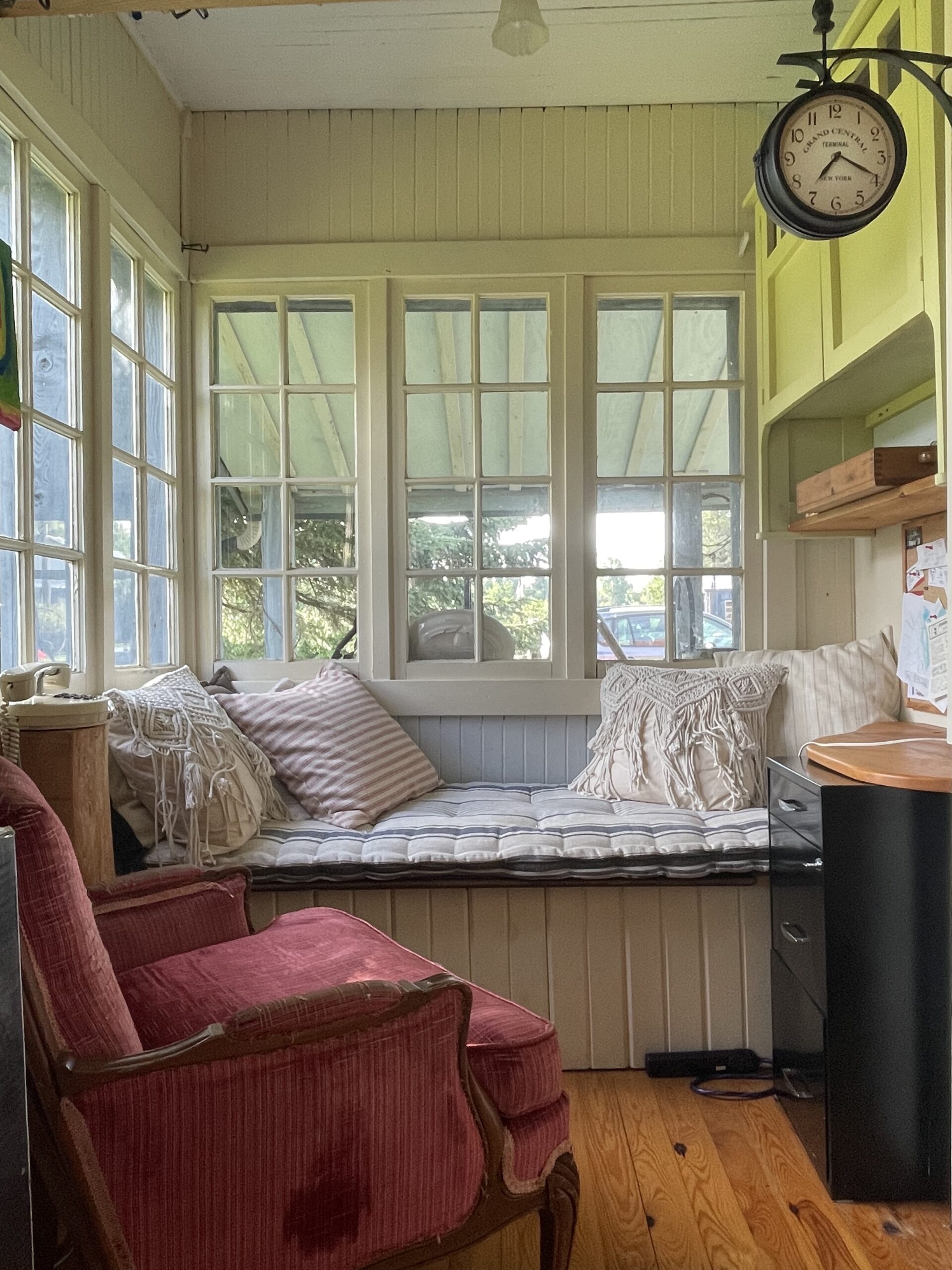 A cushioned seat in a small nook surrounded by windows.