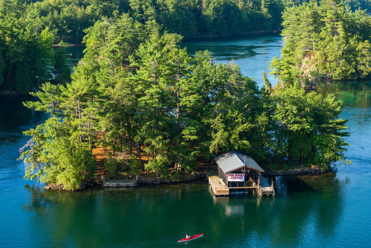 Overhead shot of an island with a cottage that has a for sale sign out front