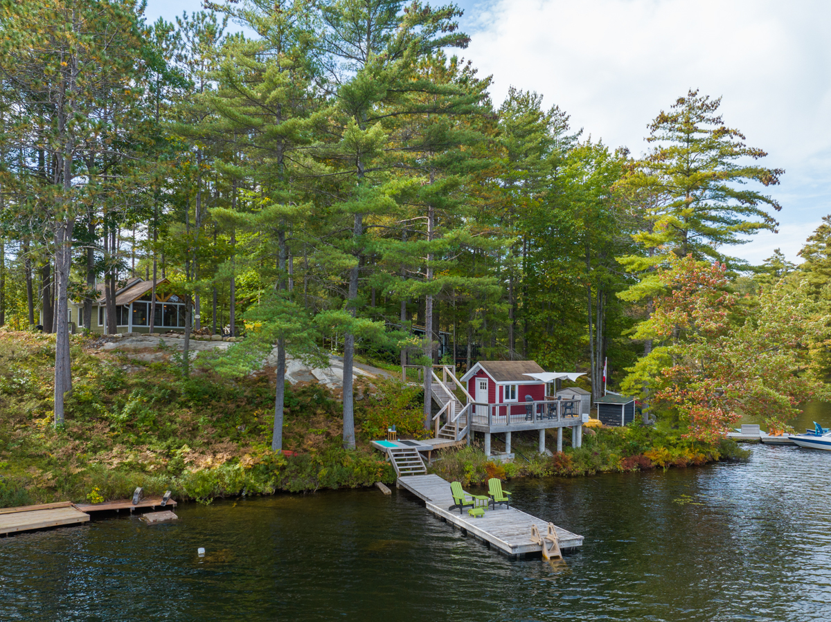 View from the water of the cottage property, including a dock, deck, and overlooking cottage