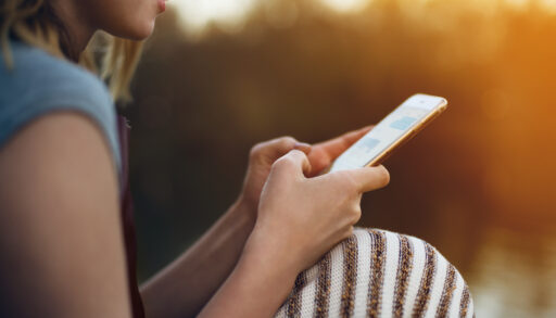 A woman texts on her smartphone outdoors
