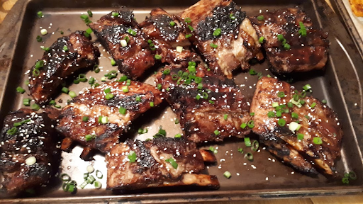 A baking sheet with ribs sprinkled with sesame seeds and green onion