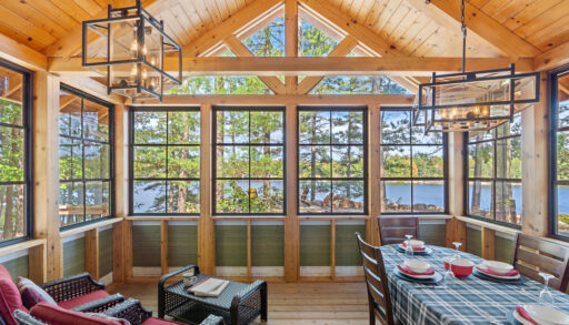 A sun room with large windows has a small lounge area to the left and a dining table to the right