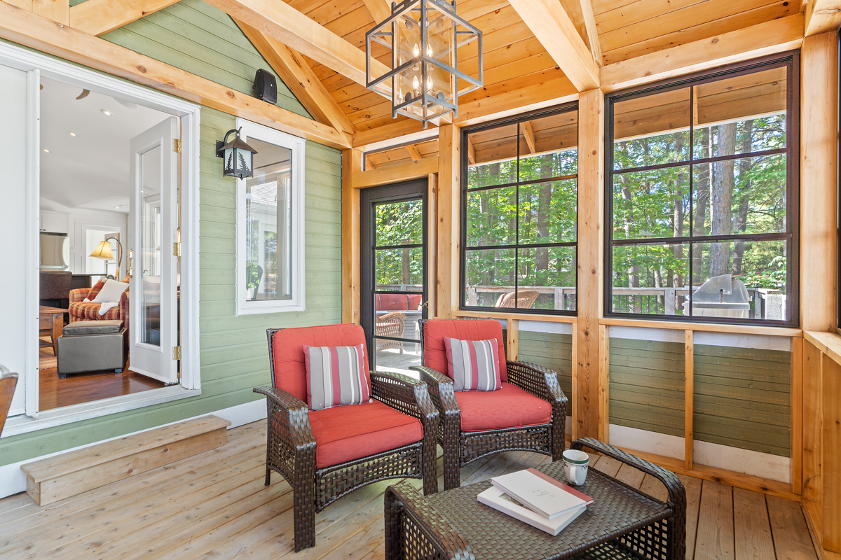 Two chairs with red cushions next to a wall of windows