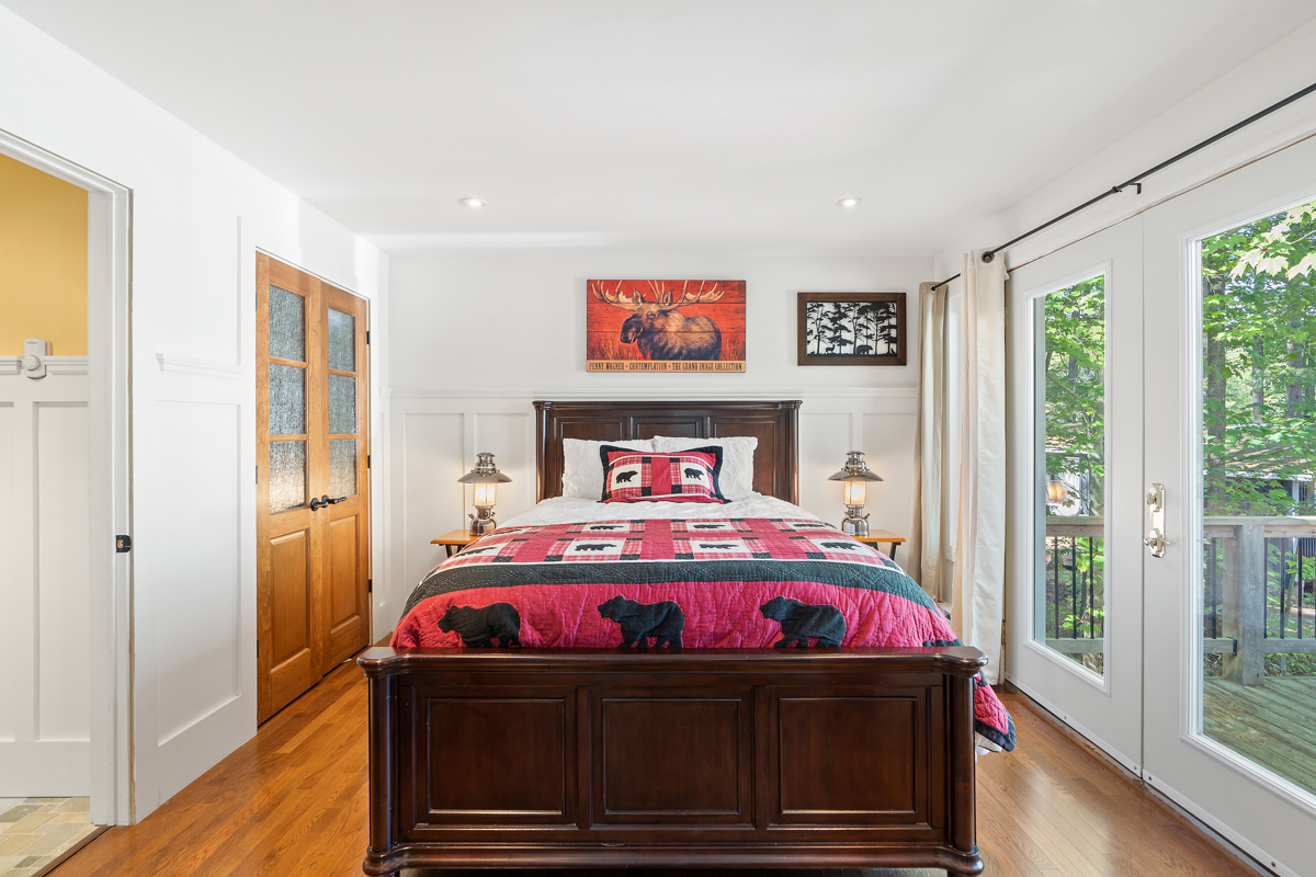 A large brown bedframe with a red bedspread with bears on it
