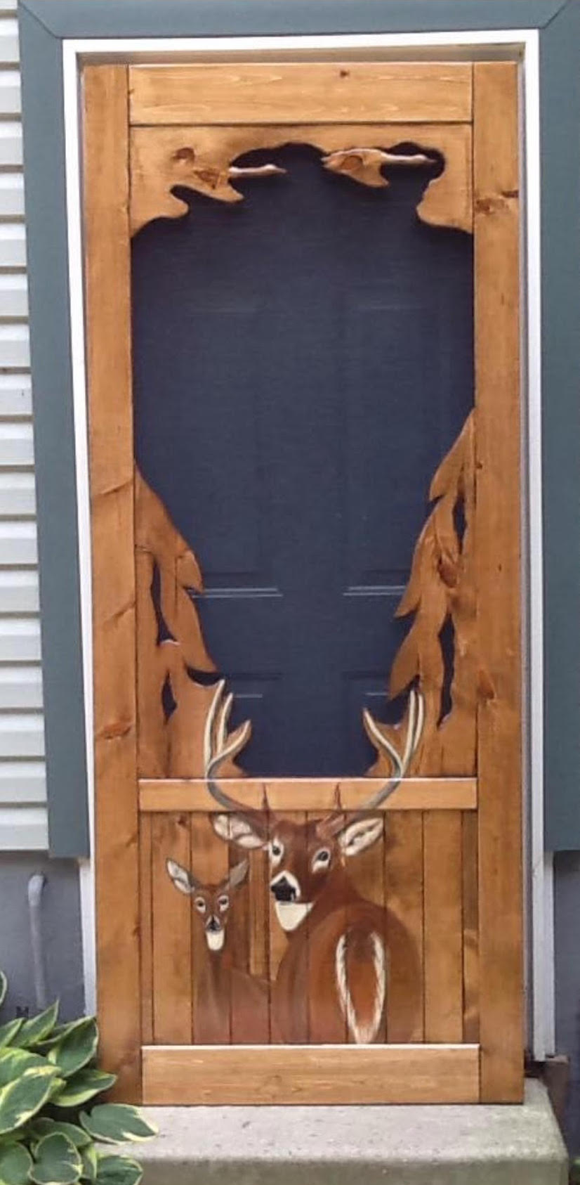 A brown screen door with two deer painted on the bottom