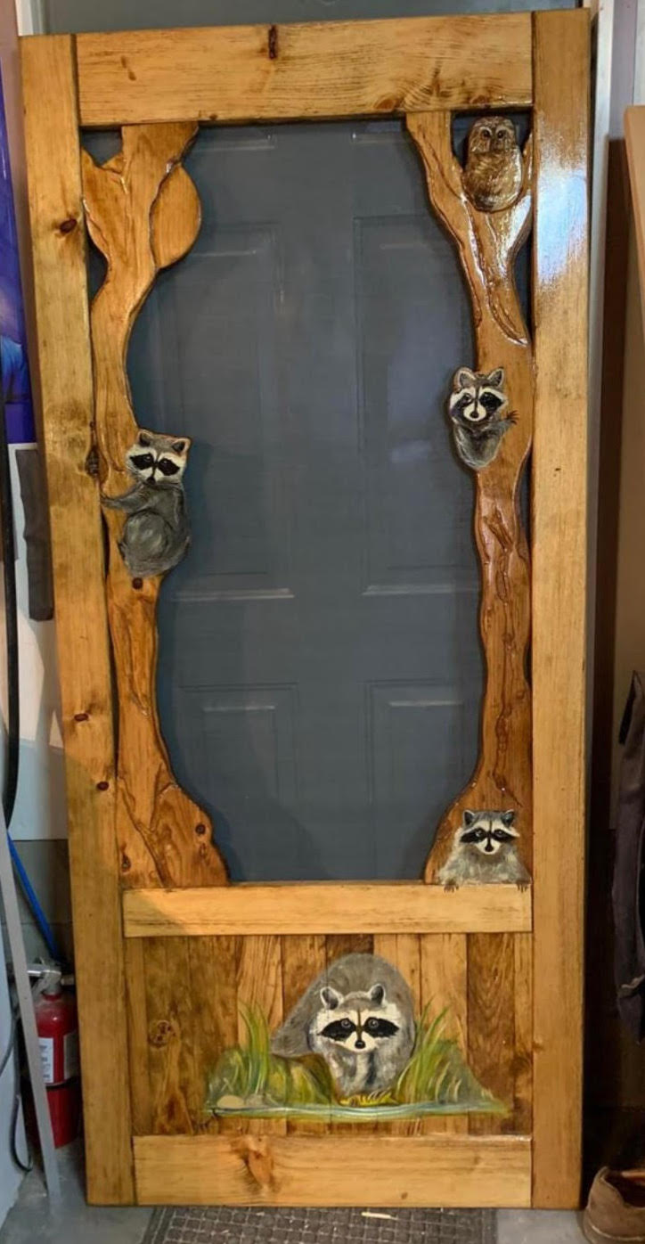 A family of raccoons are painted on this brown screen door