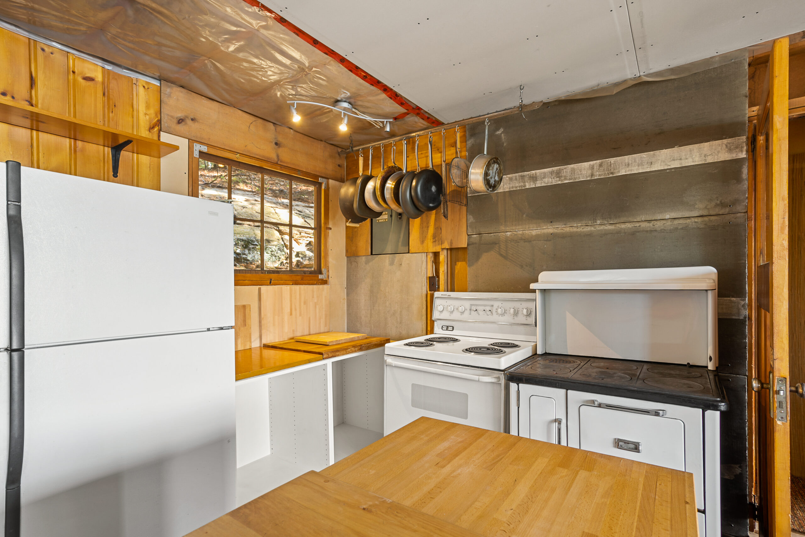 Left to right: a white fridge, counter and stove line the kitchen walls