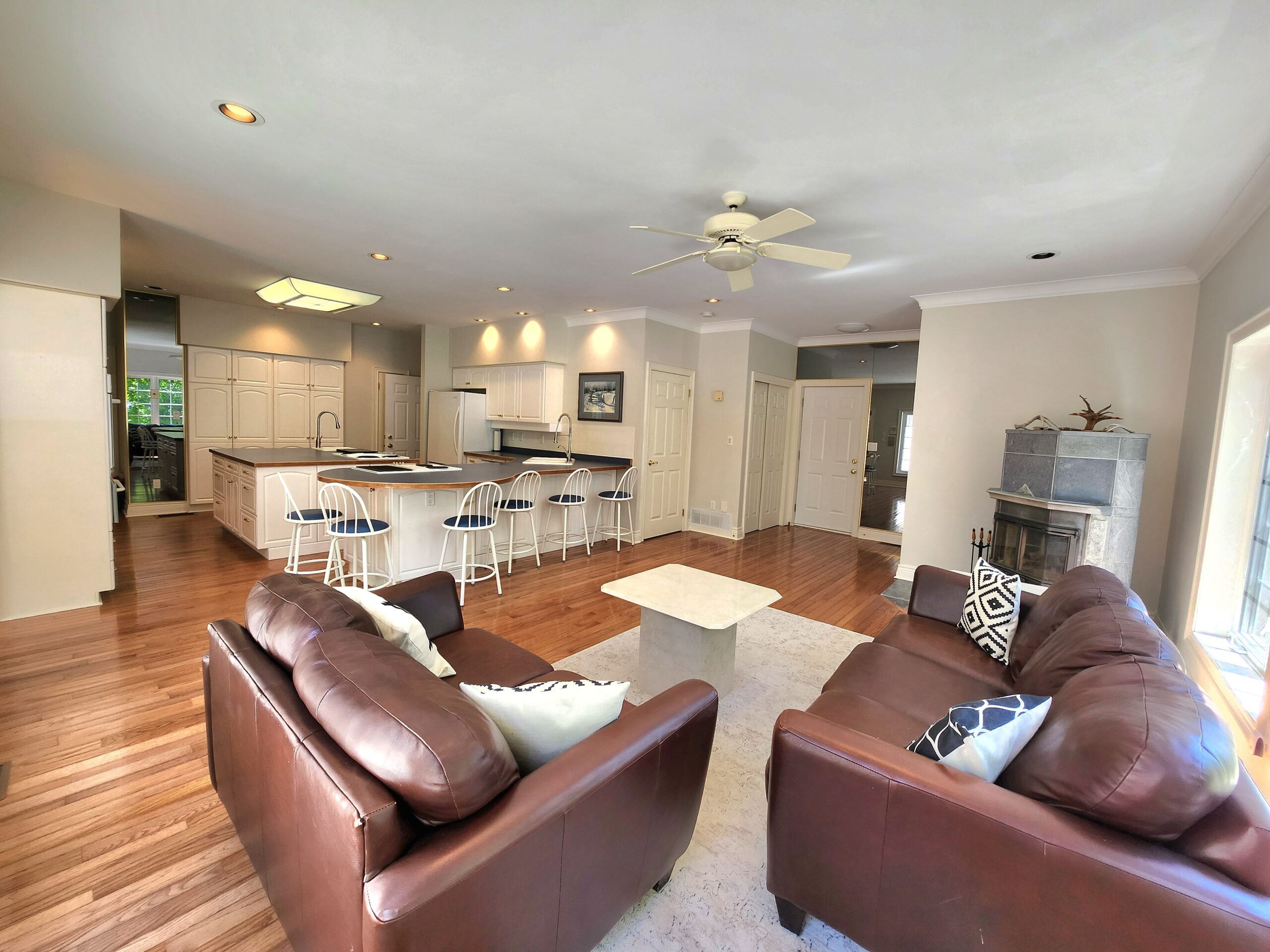 Brown leather loveseats face the kitchen