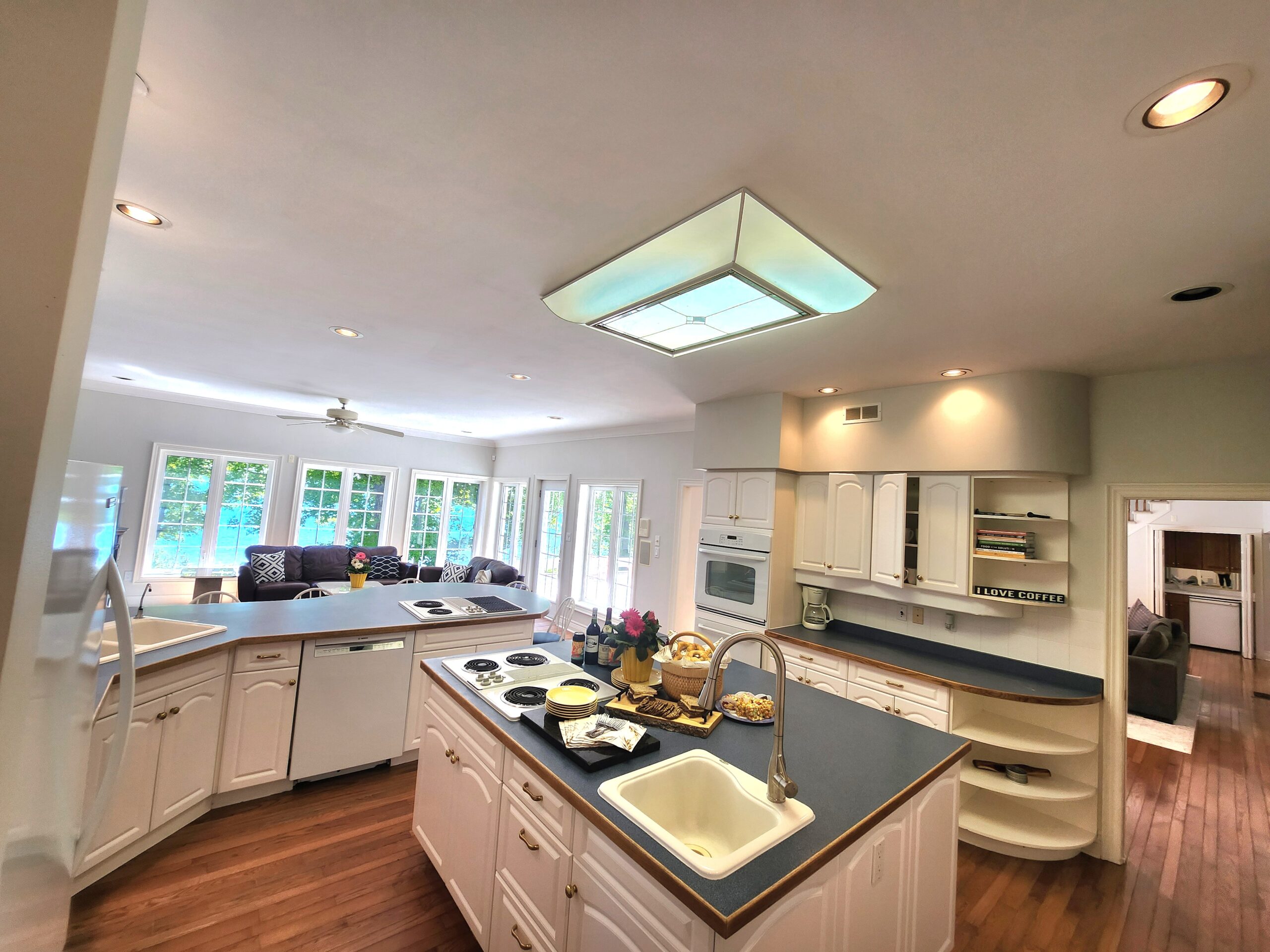 An open-concept kitchen with a large kitchen island. White cabinets with blue-grey countertops