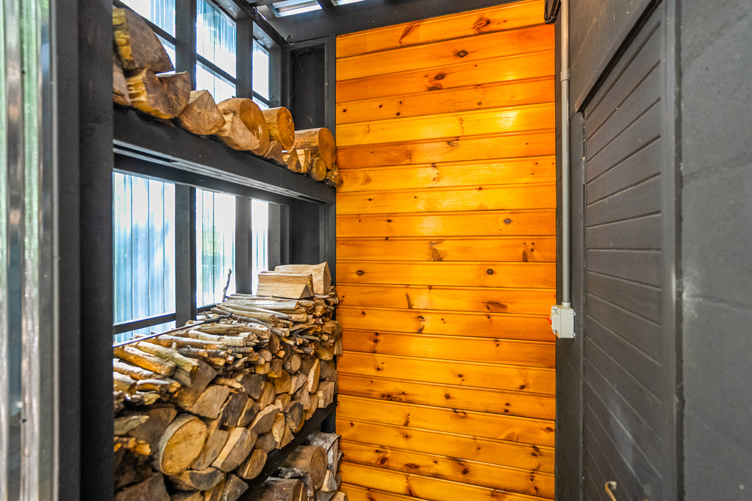 A window wall linked with stacked logs next to a wood panelled wall