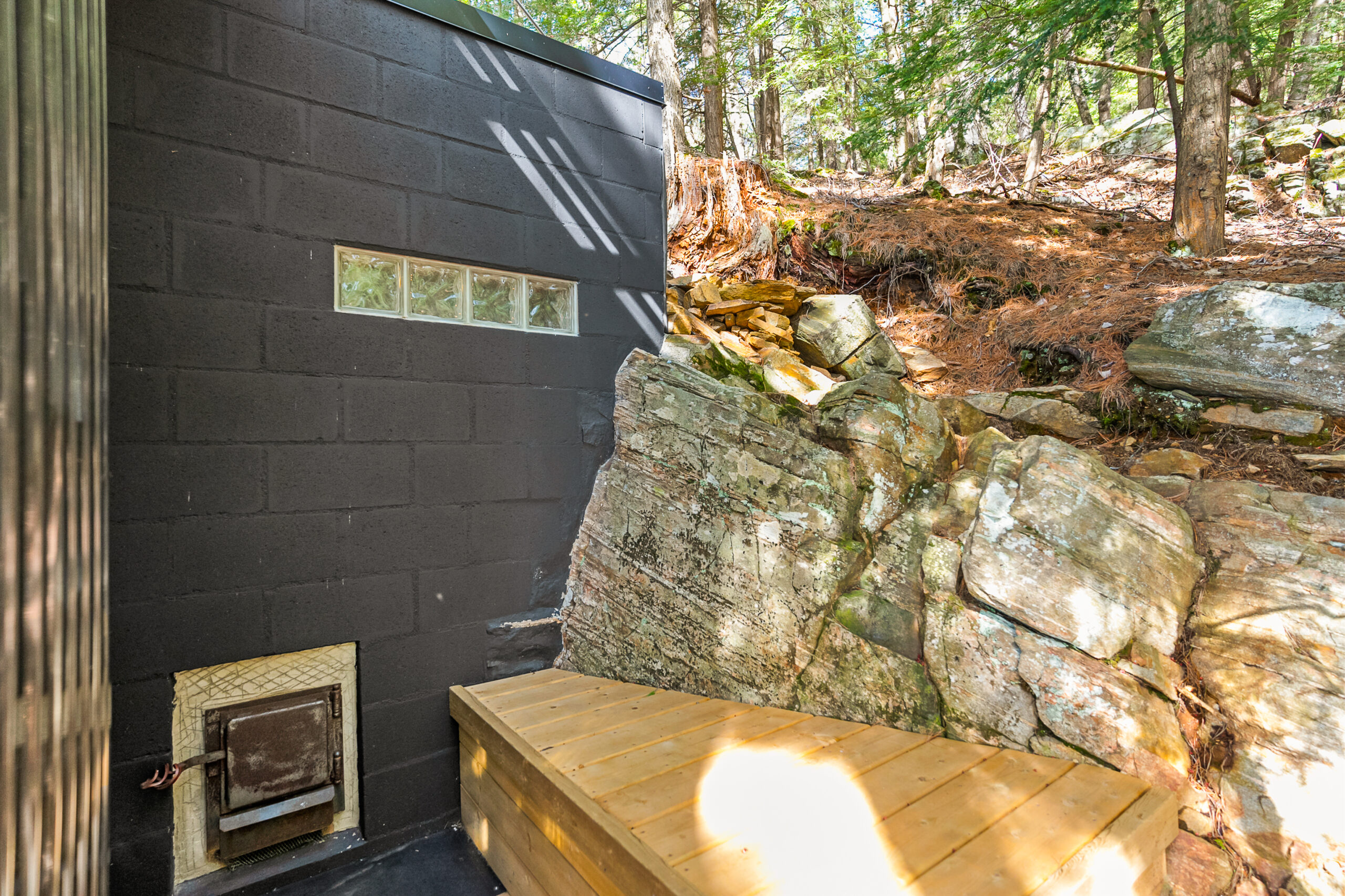 Outside the sauna is a small wood bench attached to a boulder