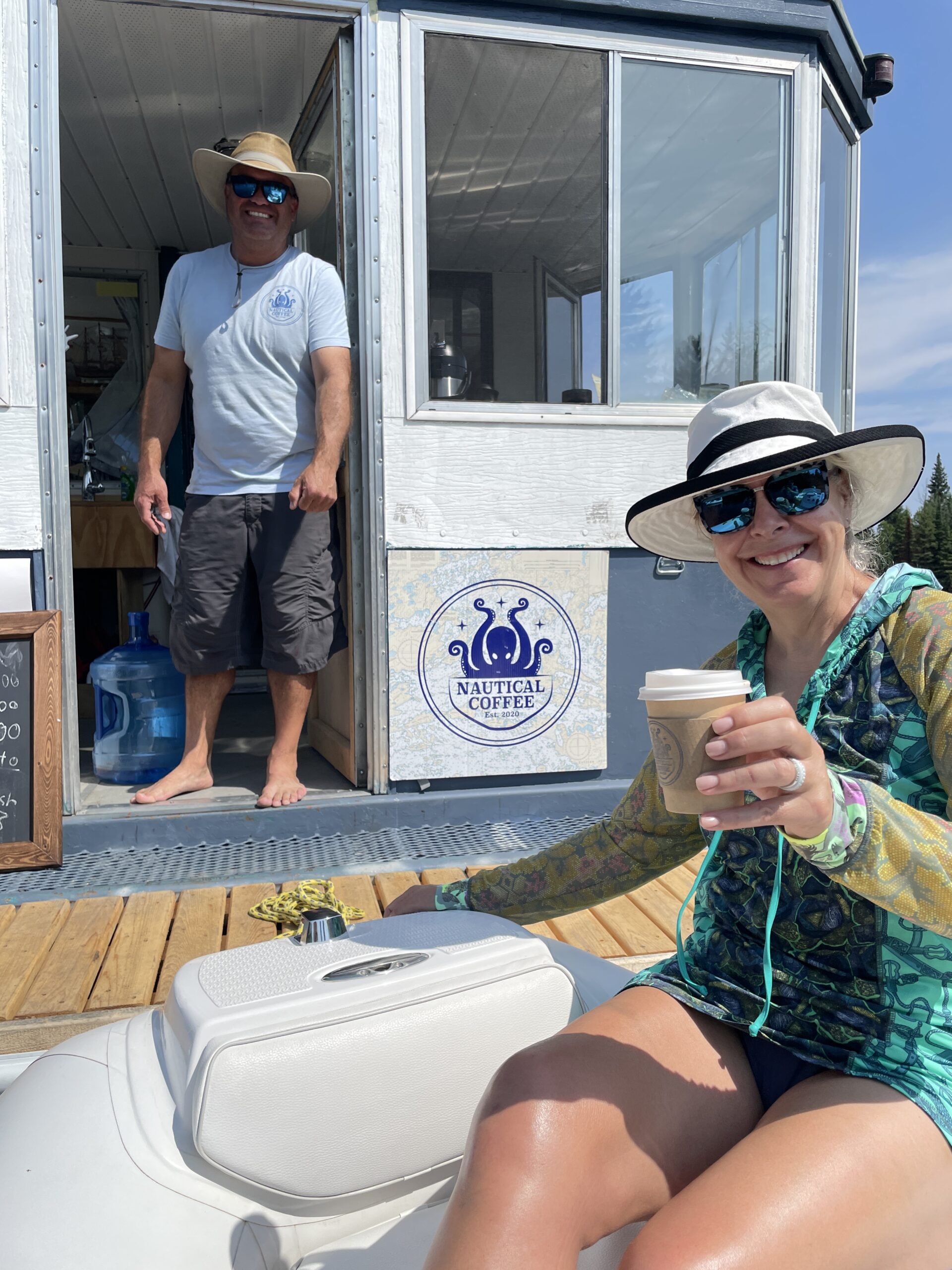 A woman holding a cup of coffee outside the roastery boat