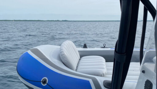 A blue and white inflatable boat sits on the edge of a police boat.