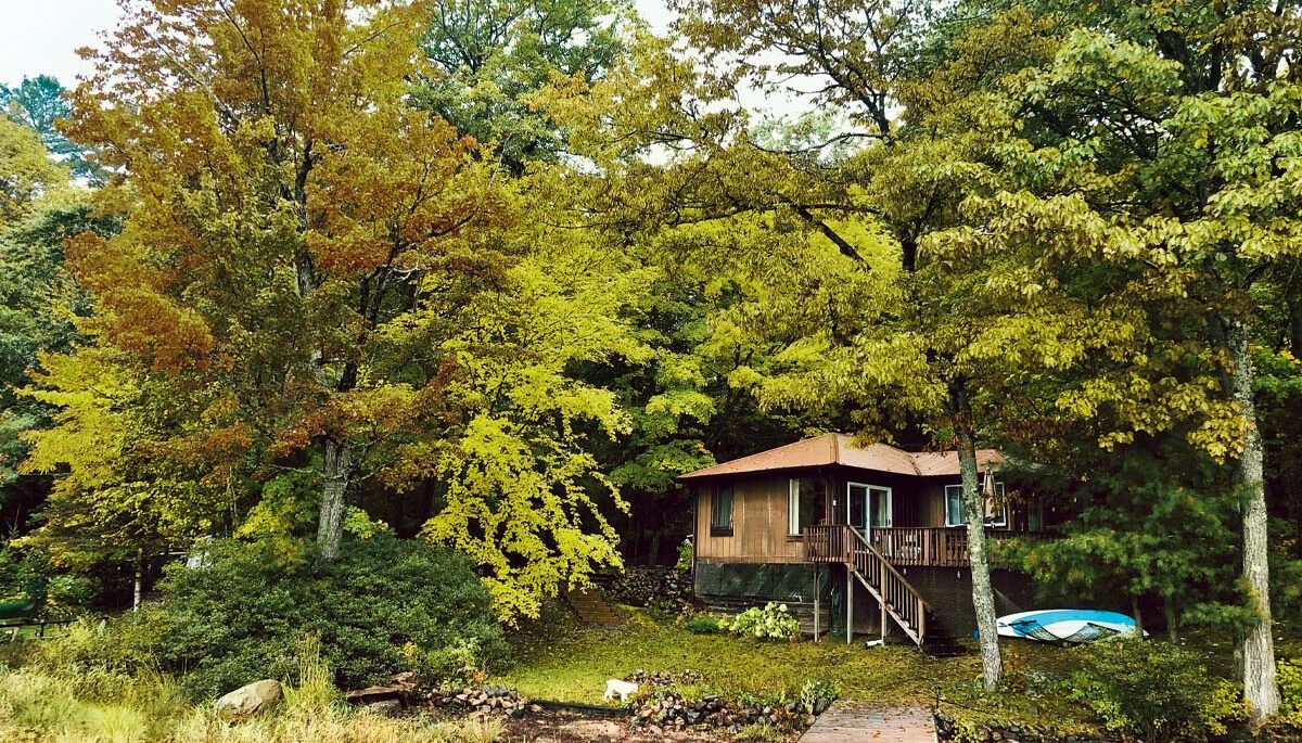 a photo of a waterfront cottage surrounded by trees