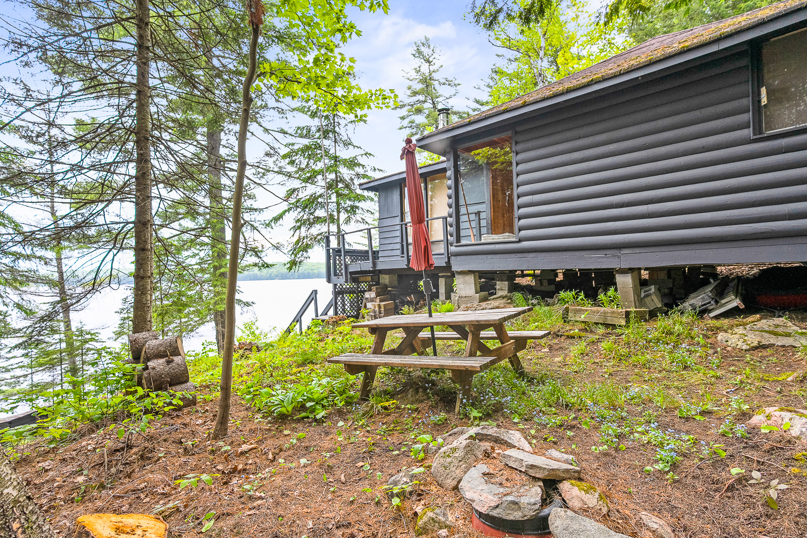 The side of the cottage has a picnic table nestled in the woods