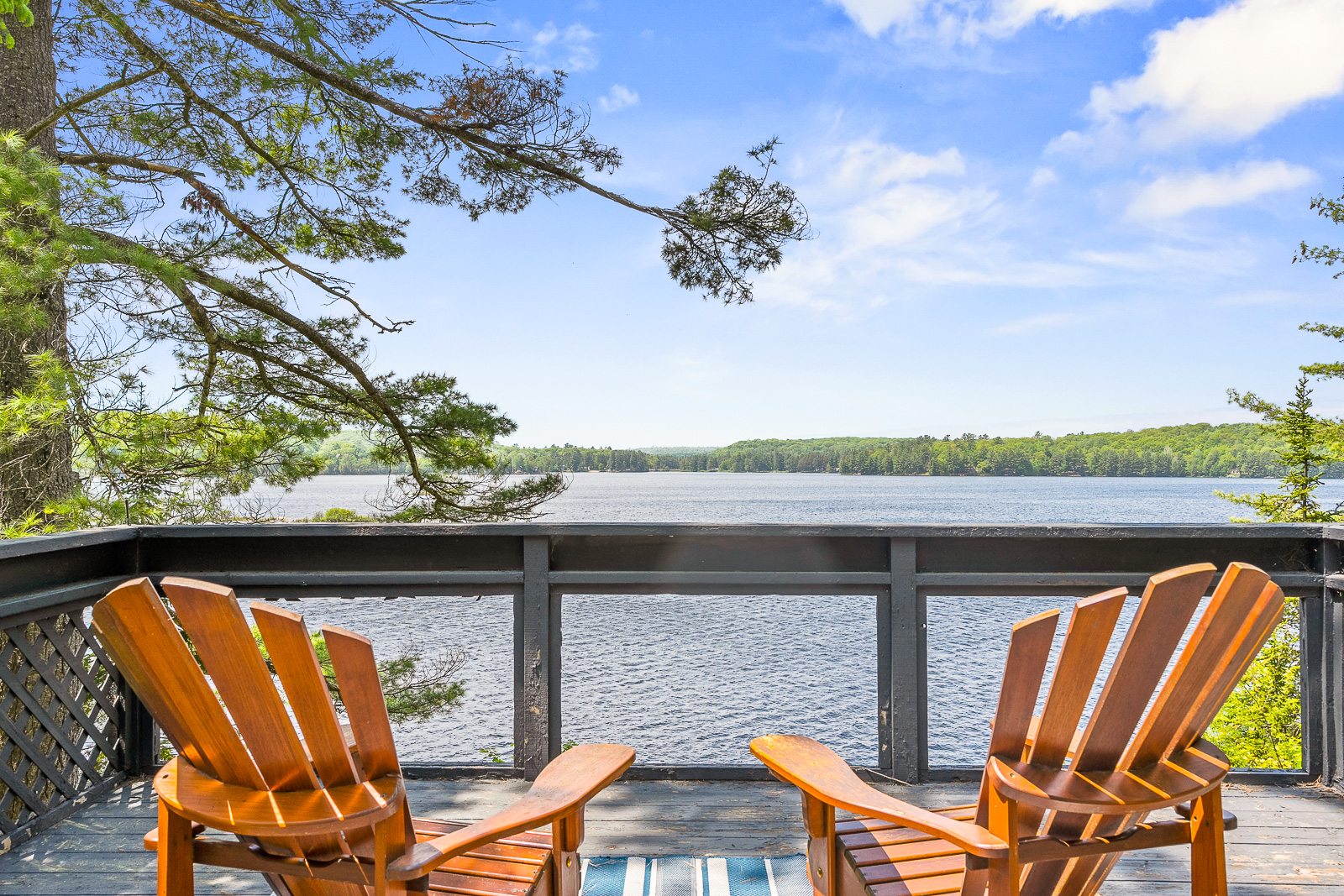 From behind, two brown Muskoka chairs face the lake