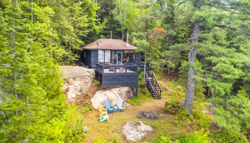 Aerial view of the back of the grey cottage with the bright coloured Muskoka chairs
