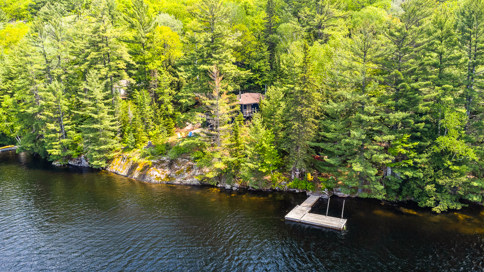 a drone shot of a waterfront cottage in a wooded area