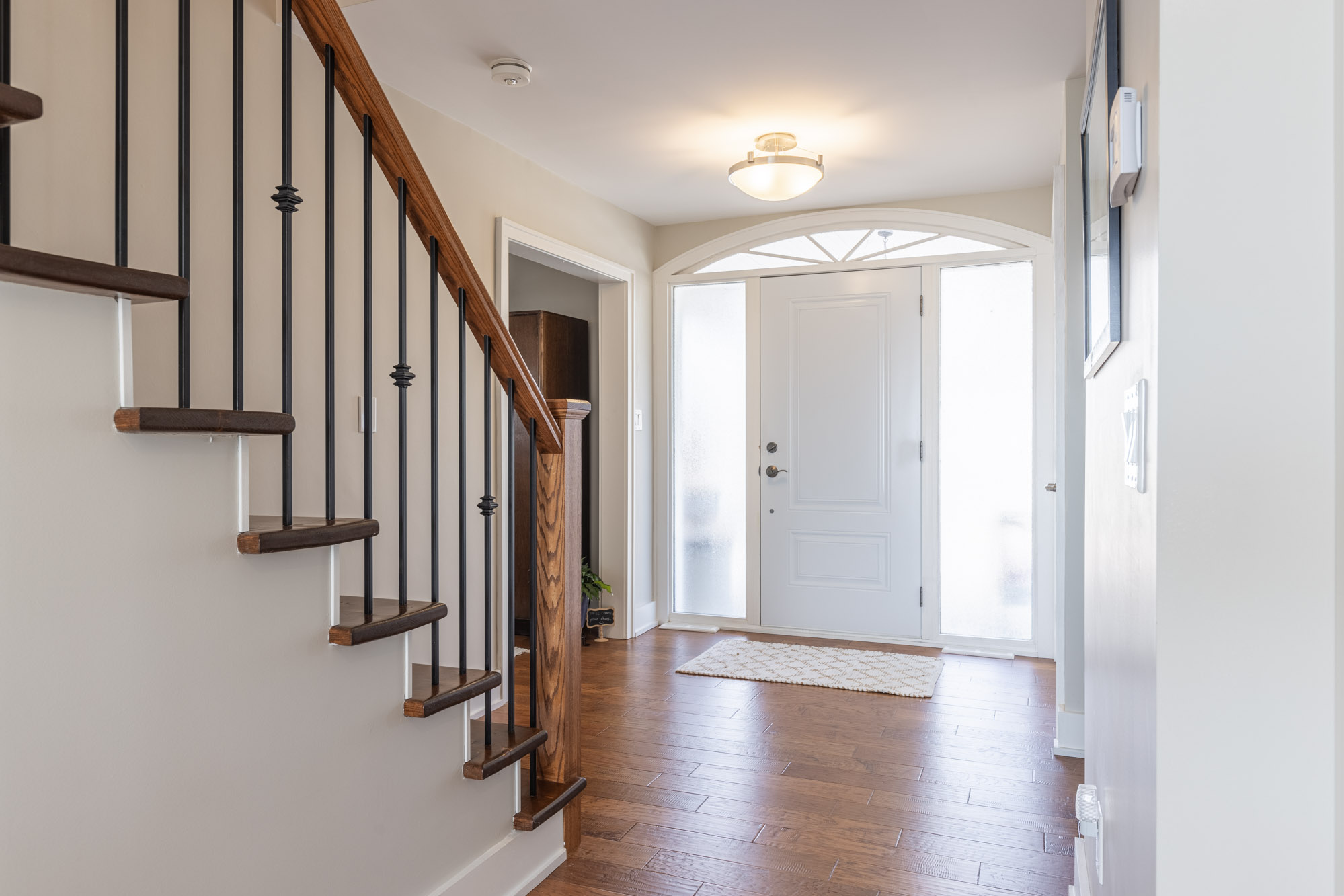 An entryway with dark hardwood floors and a stair case facing the front door